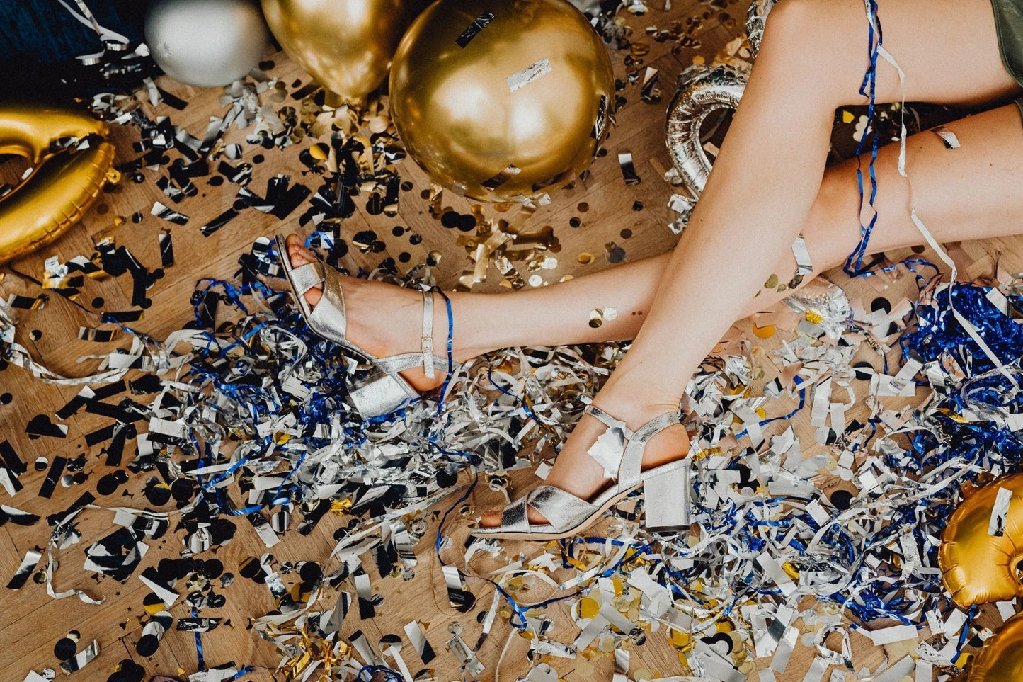 Silver heels surrounded by gold balloons, confetti and party decorations after a fun hen party celebration.