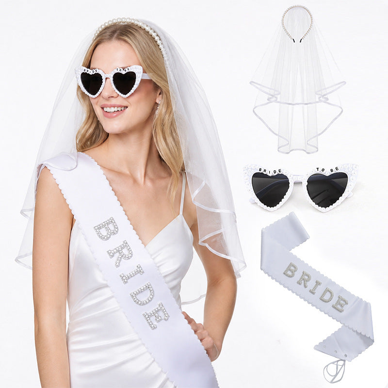 Bride accessory set featuring a white veil, heart-shaped sunglasses, a white 'BRIDE' sash, and a white veil headband.
