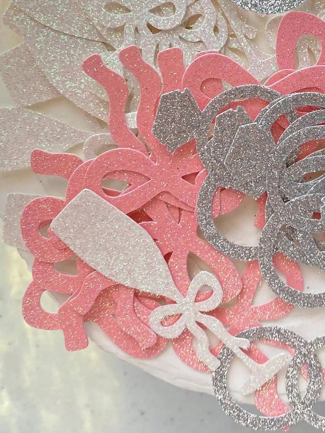 Decorative confetti with pink and silver colours on a textured background
