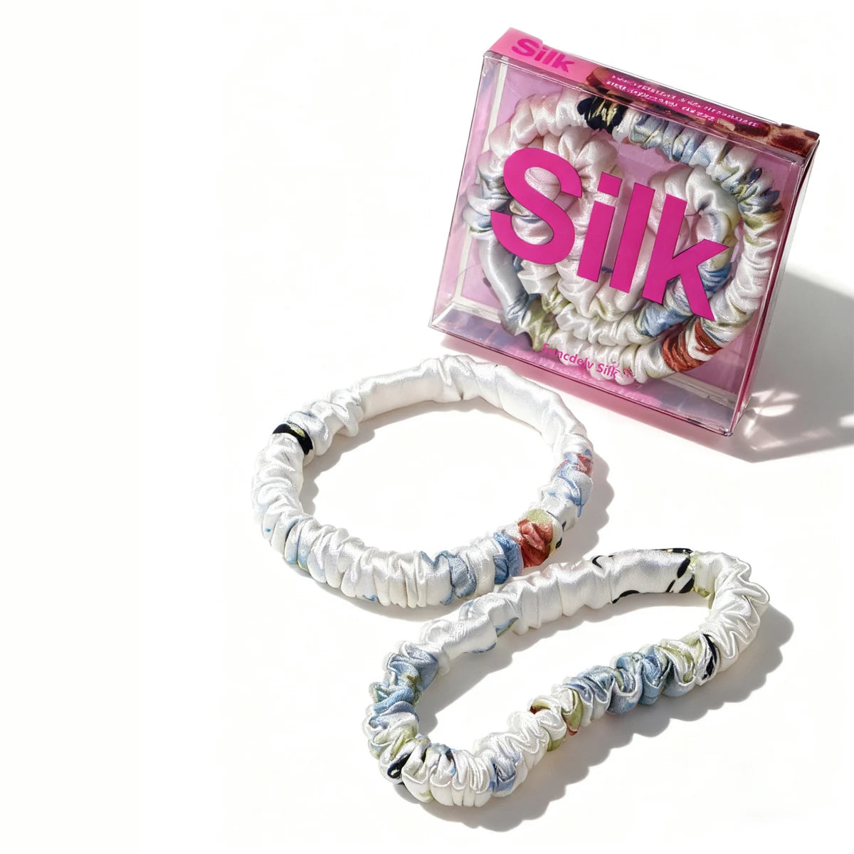 Colorful hair ties with a 'Silk' branded box on a white background