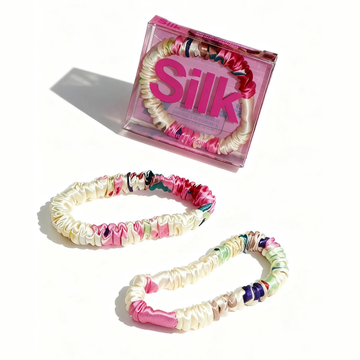 Set of colorful hair ties with a pink 'Silk' box on a white background