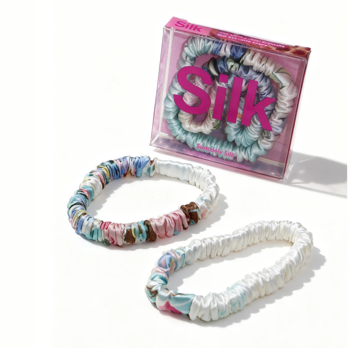 Colorful hair ties with a 'Silk' branded box on a white background