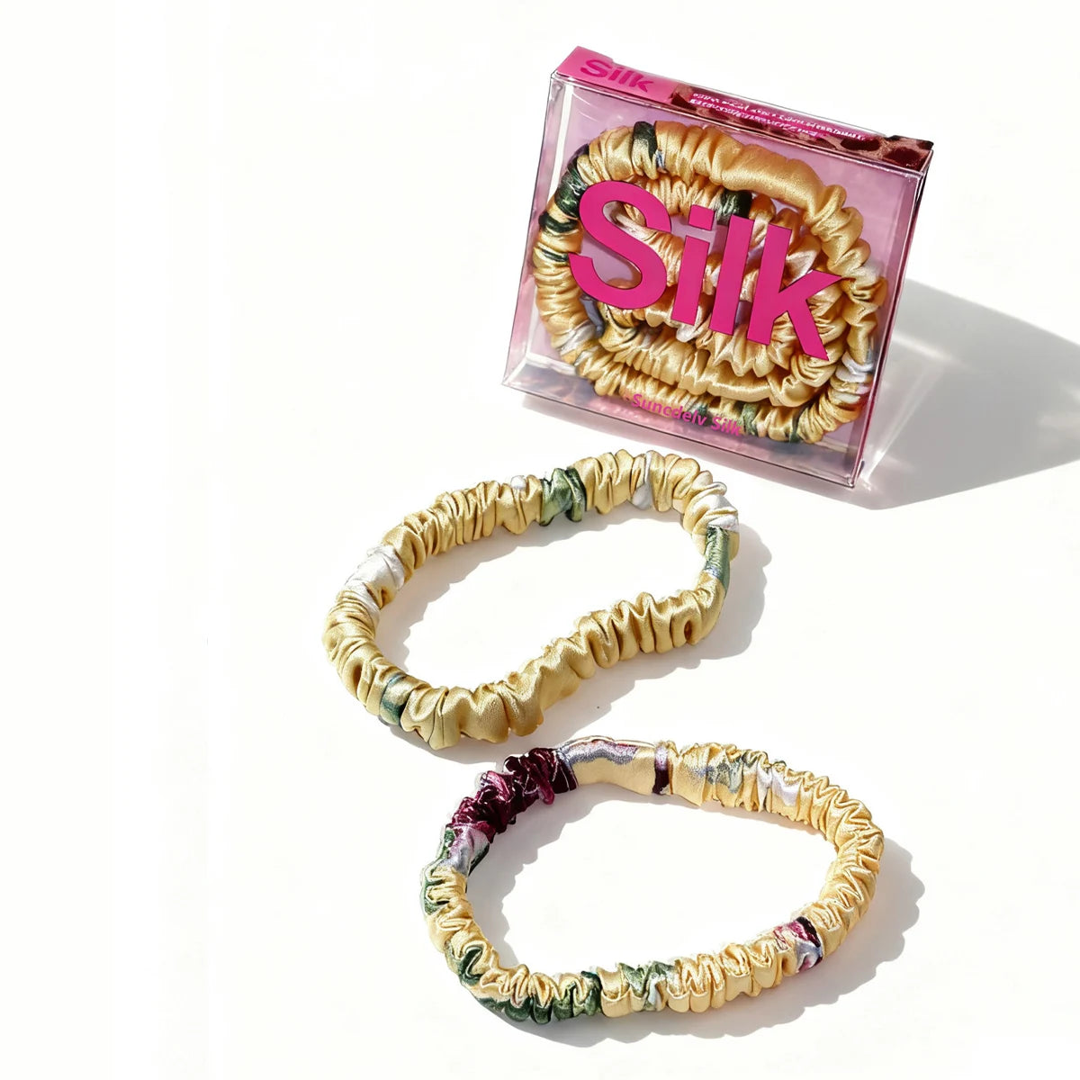 Colorful hair ties with a 'Silk' branded box on a white background