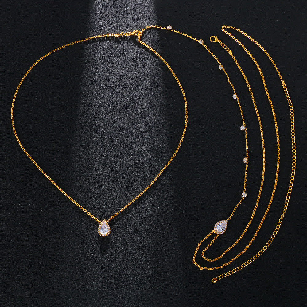 Gold necklace with a teardrop-shaped pendant on a black background