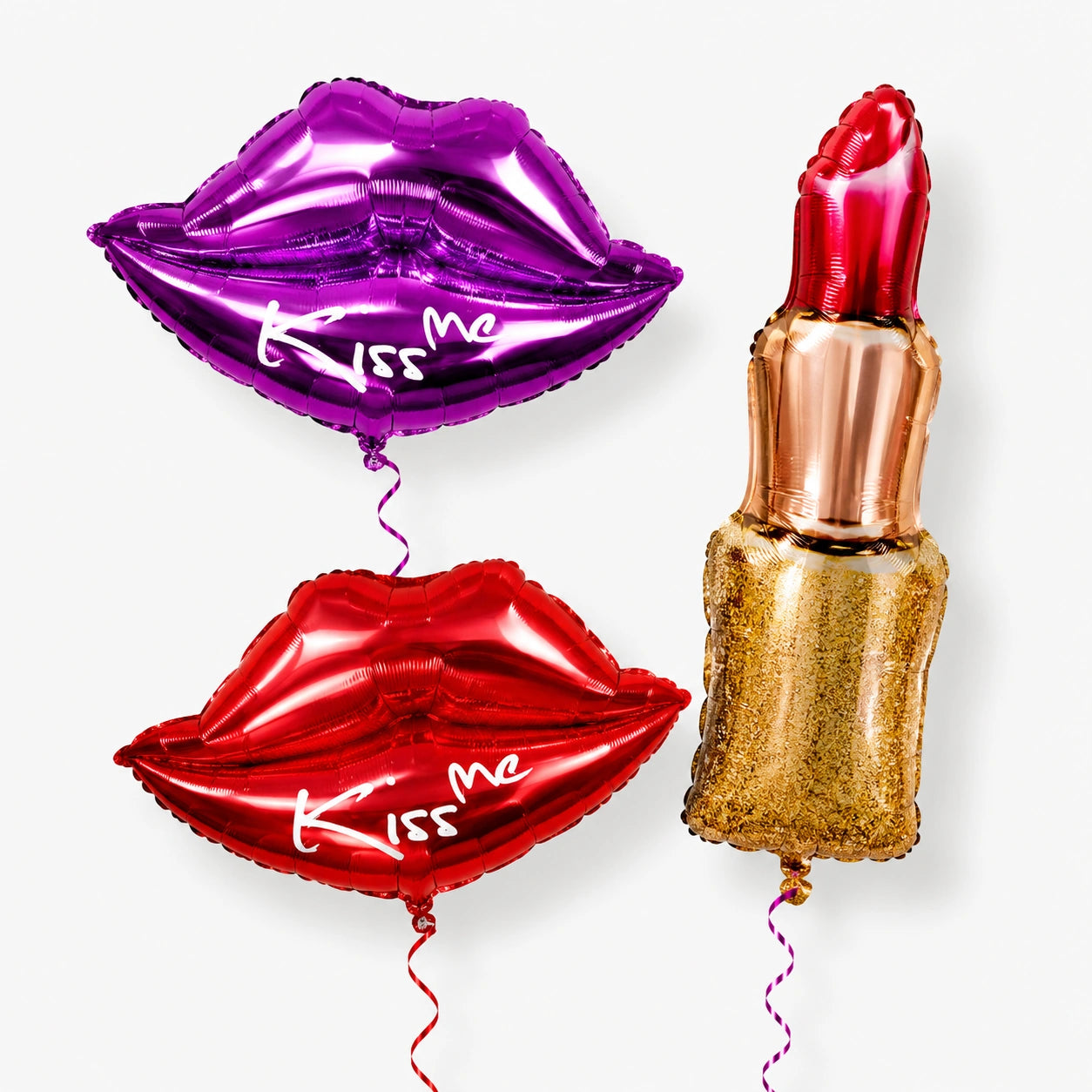 Three oversize balloons: red lips with 'Kiss me', purple lips with 'Kiss me', and lipstick.