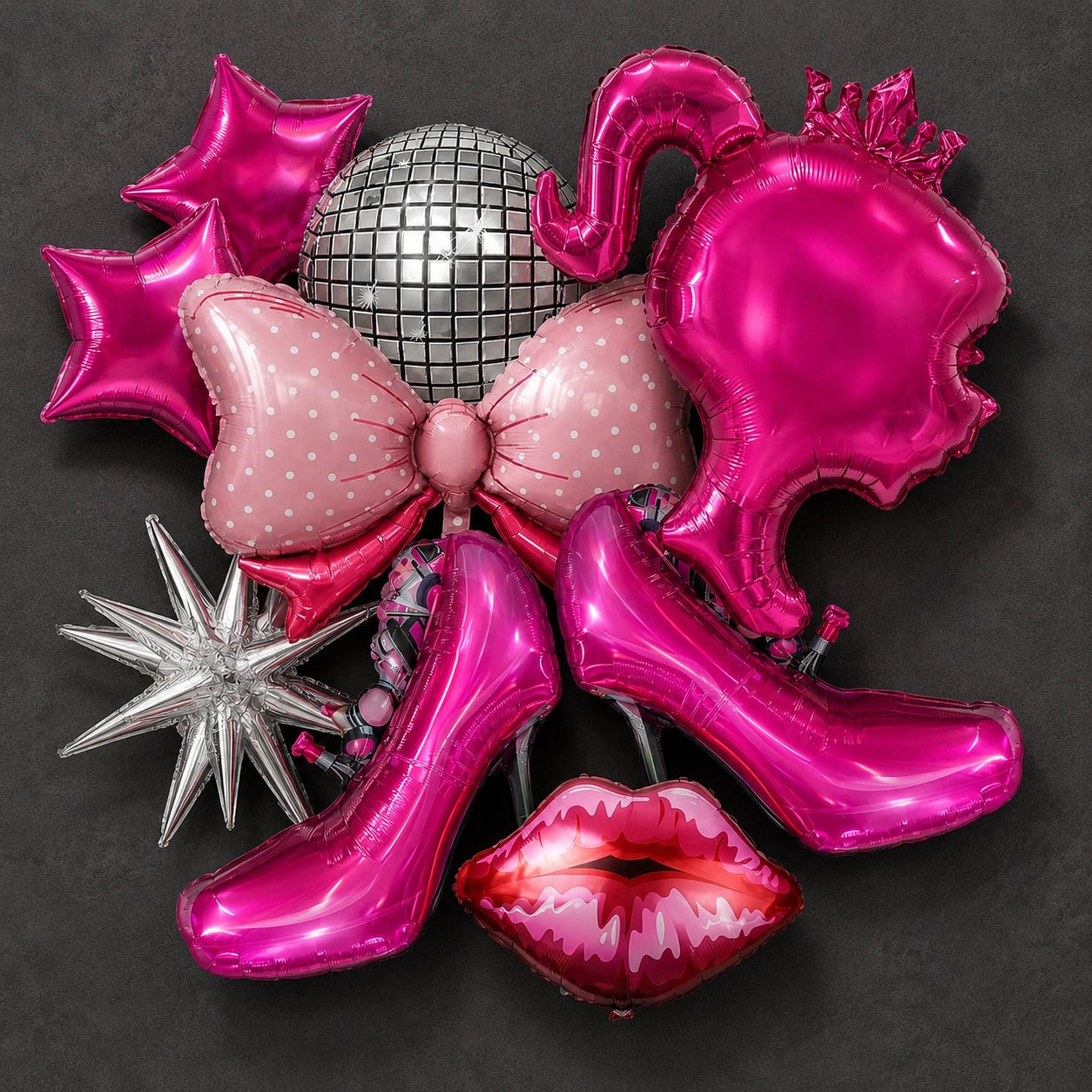 A collection of metallic pink and silver party balloons arranged on a dark gray background, including a disco ball, bow, stars, high heels, lips, and a crown-shaped balloon.