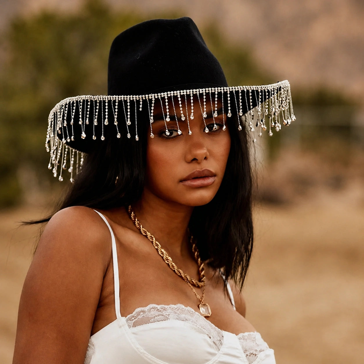Woman wearing a black hat with tassels against a blurred natural background