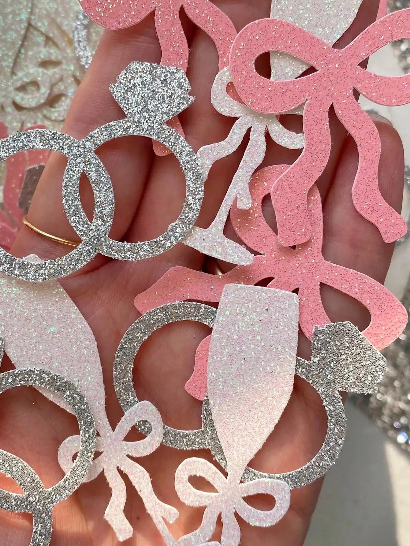 Decorative confetti of rings and bows with glittery textures.