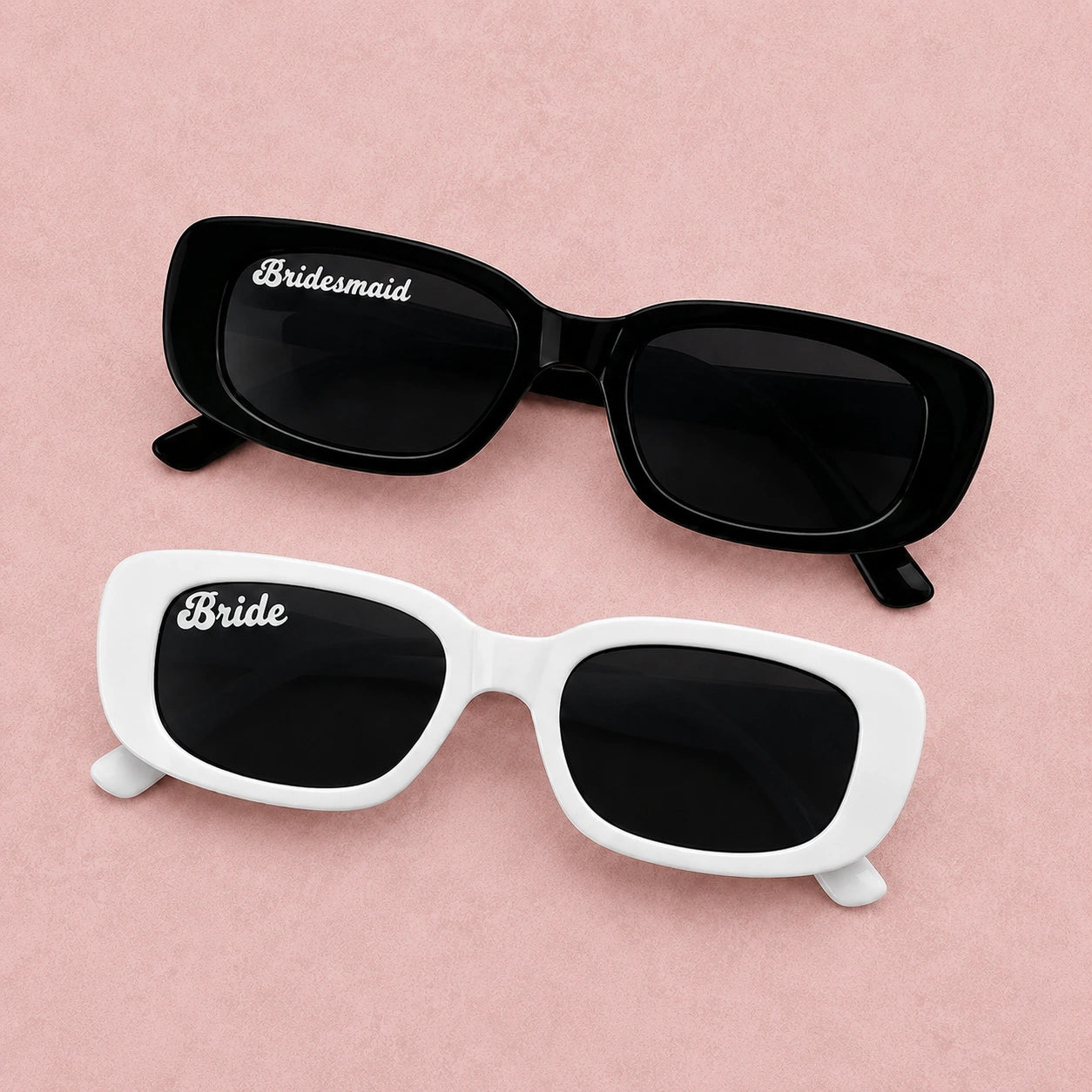 Black and white sunglasses with 'Bride' and 'Bridesmaid' text on a pink background