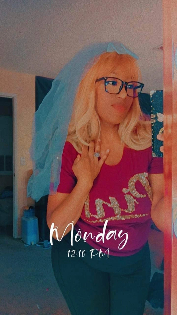 Woman taking a mirror selfie while wearing a white veil and pink bride shirt