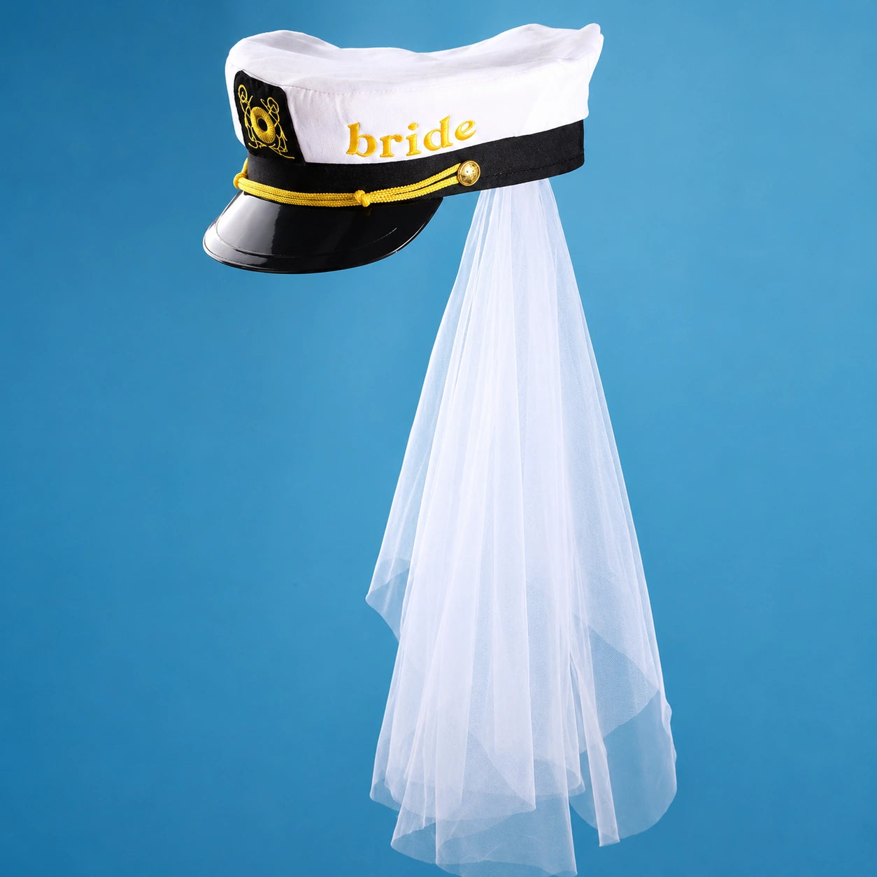 A novelty bride costume hat styled like a captain's hat, featuring a white top with 'bride' written in gold, a black band, gold trim, and a long white tassel veil, shown against a solid blue background.