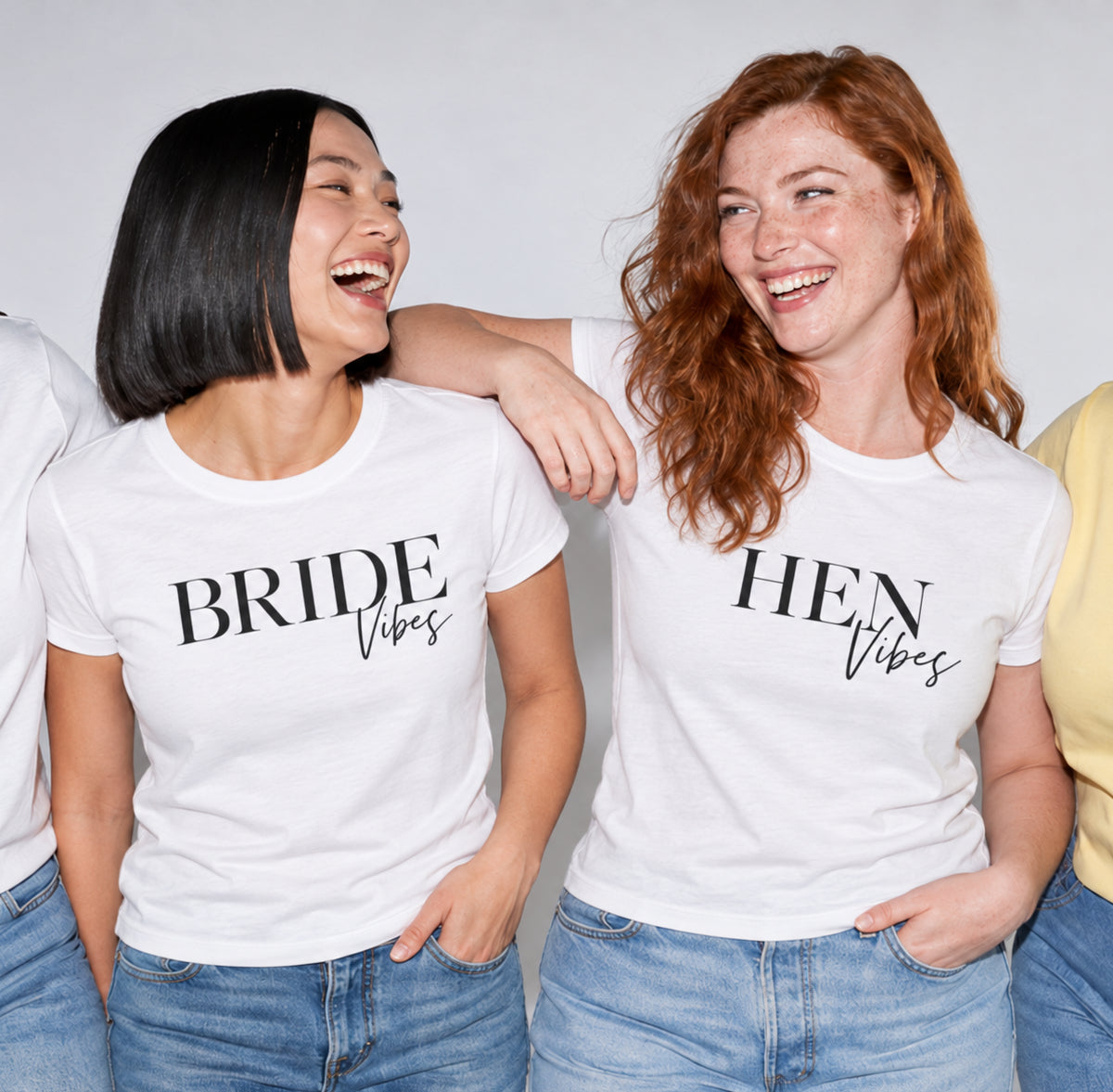 Two women laughing and wearing matching white graphic T-shirts that read 'BRIDE Vibes' and 'HEN Vibes' in black lettering.