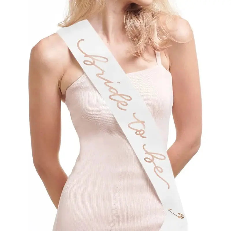 Woman wearing a 'Bride to Be' sash on a white background
