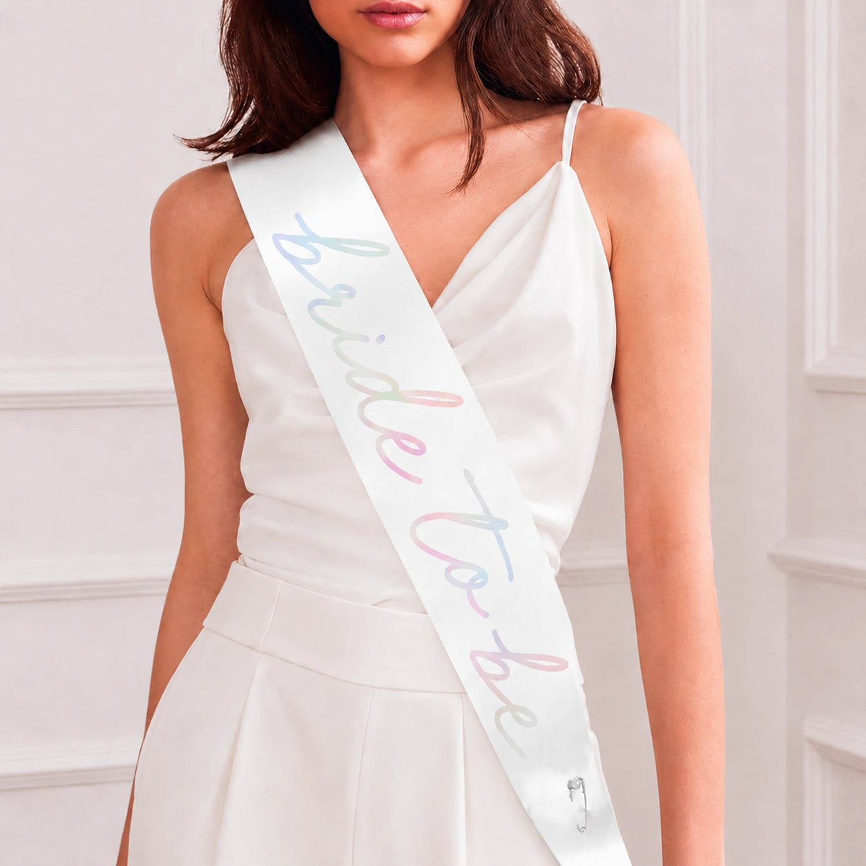 Woman wearing a white dress with a 'bride to be' sash against a light background