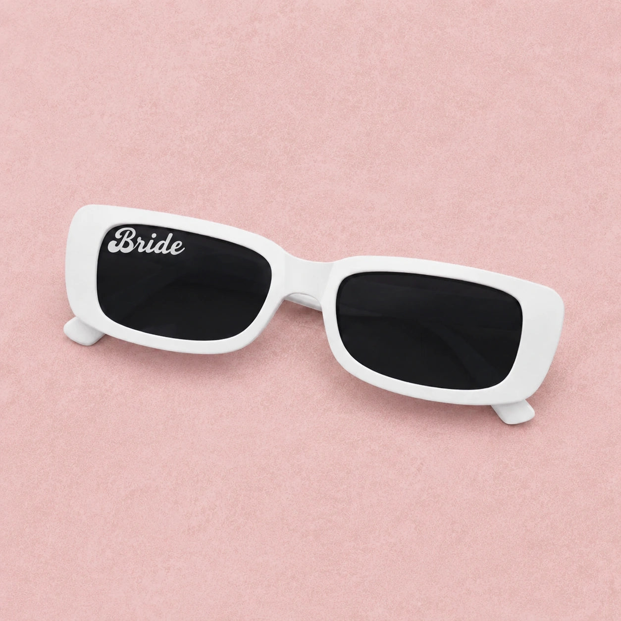 White sunglasses with 'Bride' on a pink background
