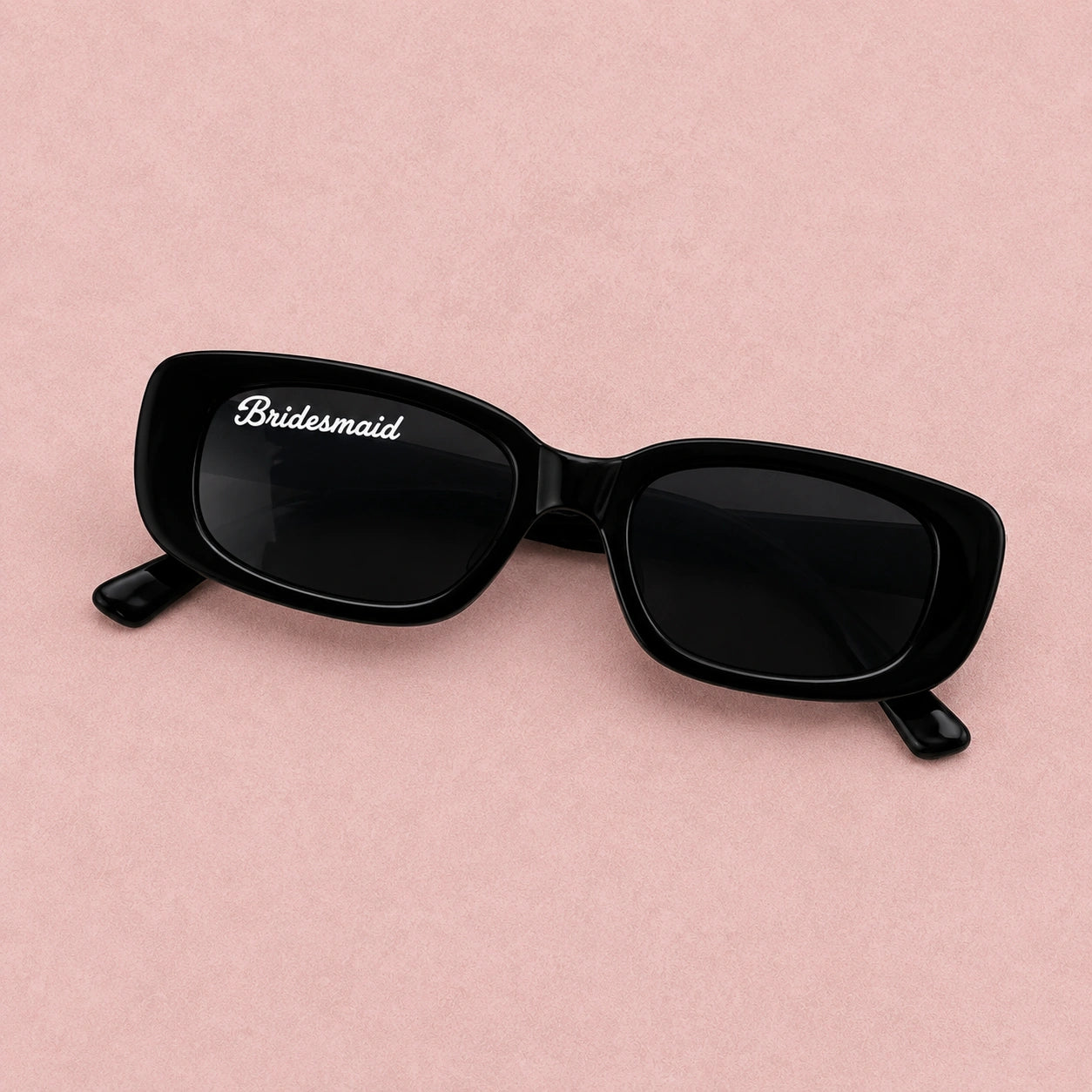 Black sunglasses with 'Bridesmaid' on a pink background