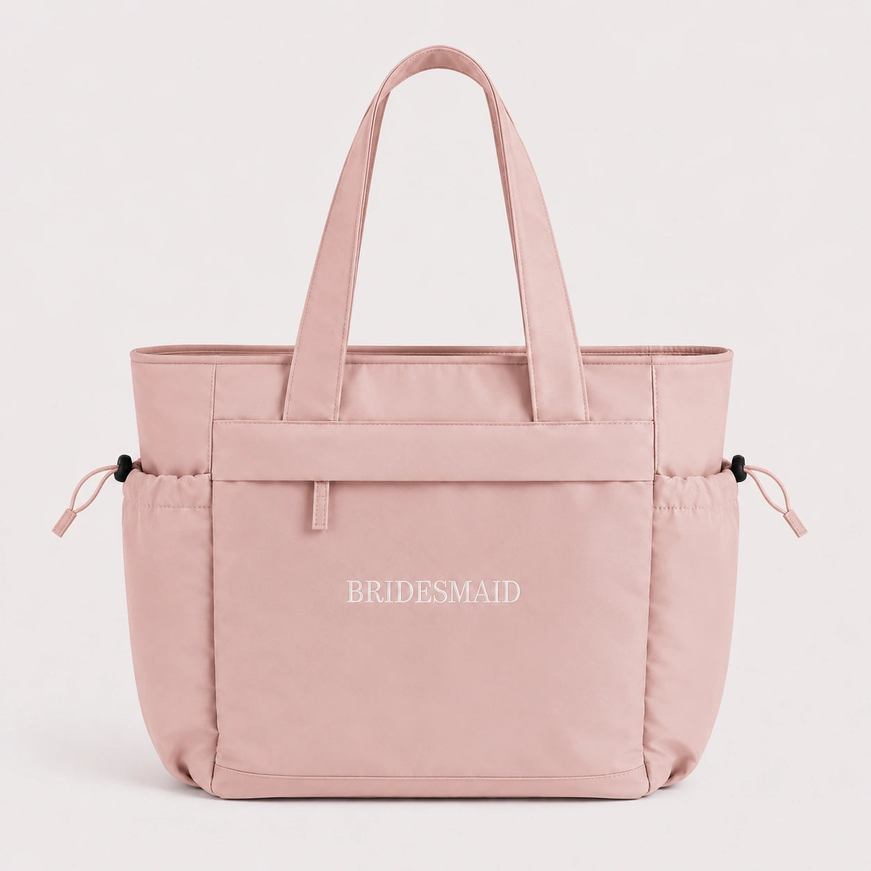Pink tote bag with 'BRIDESMAID' text on a light pink background