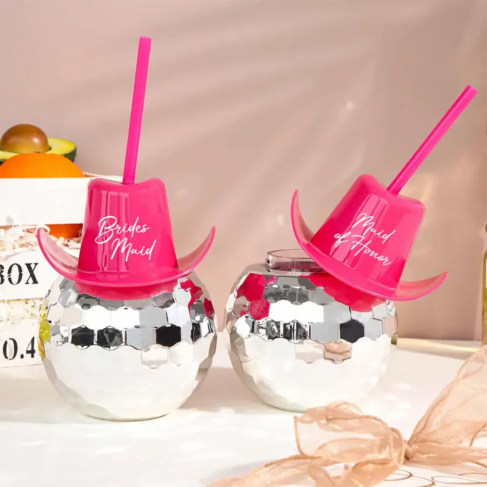 Two silver disco ball cups with pink hats labeled 'Bridesmaid' and 'Maid of Honor' on a light background.