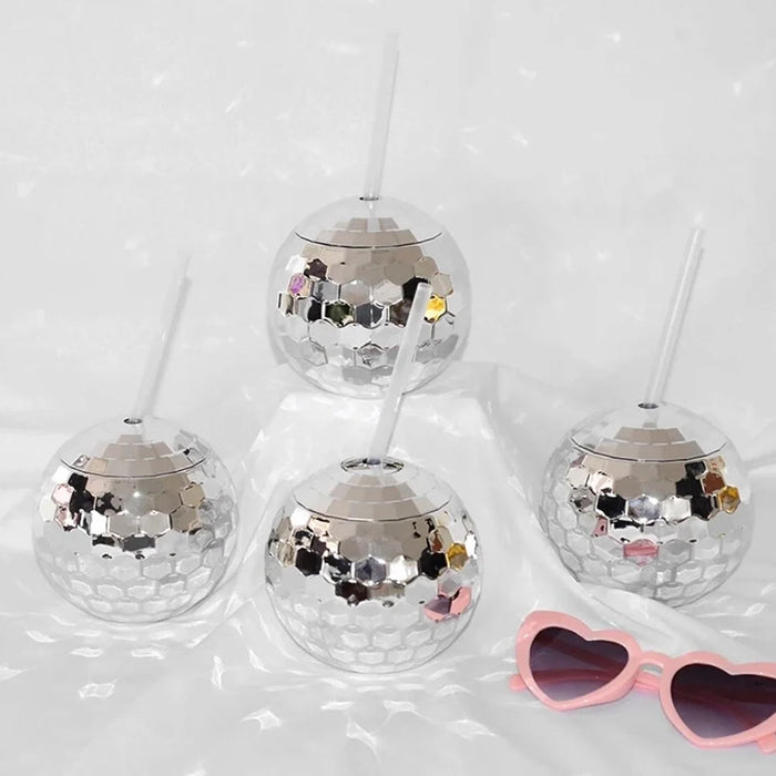 Set of silver disco balls with a pair of pink heart-shaped sunglasses on a white background