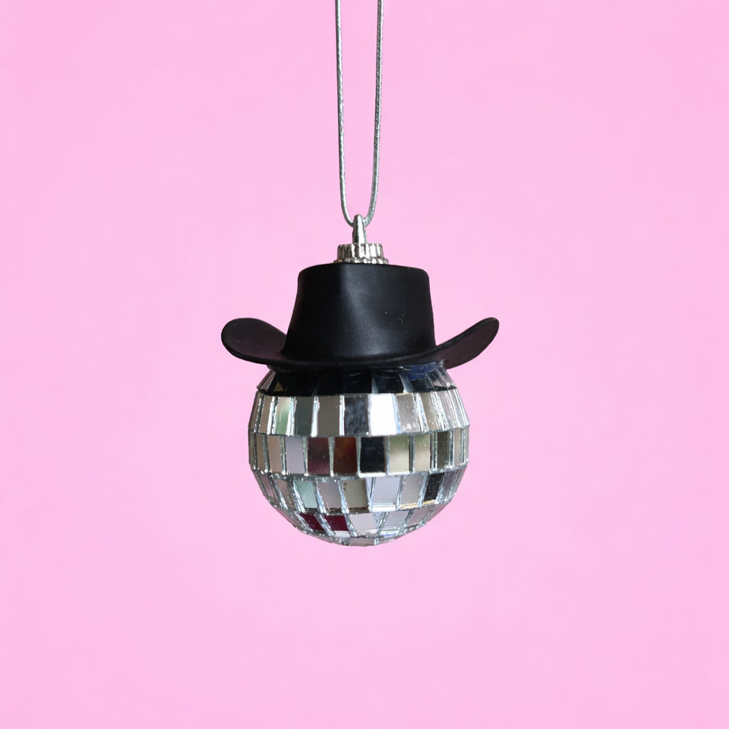 Black disco cowgirl car mirror charm with a mini cowboy hat and mirrored disco ball on a soft pink background.