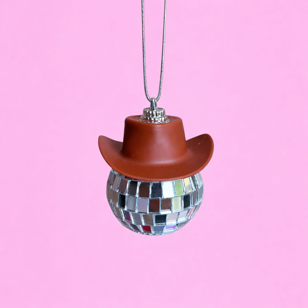 Brown disco cowgirl car mirror charm with a mini cowboy hat and mirrored disco ball on a soft pink background.