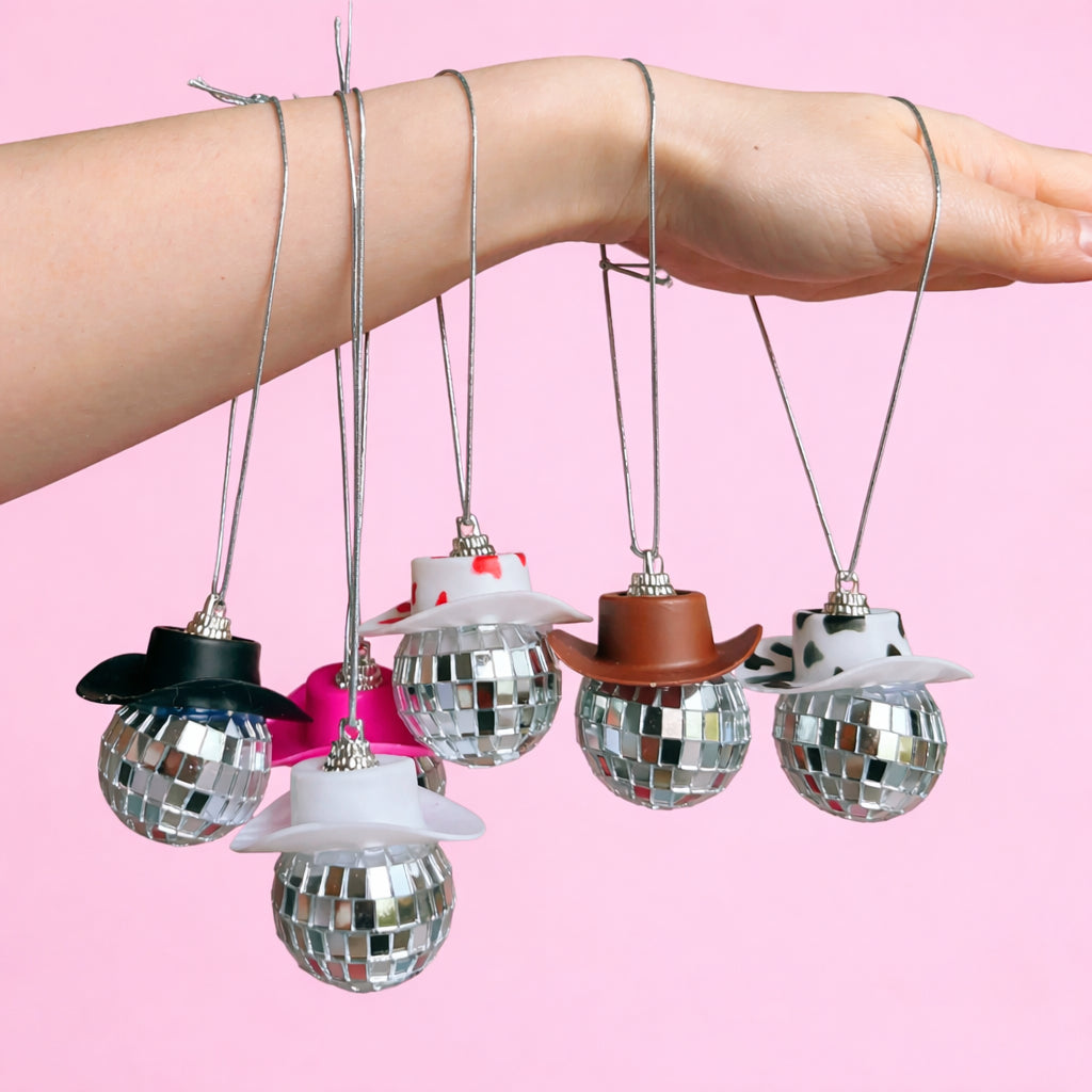 Disco cowgirl car mirror charms with mini cowboy hats and mirrored disco balls on a soft pink background.