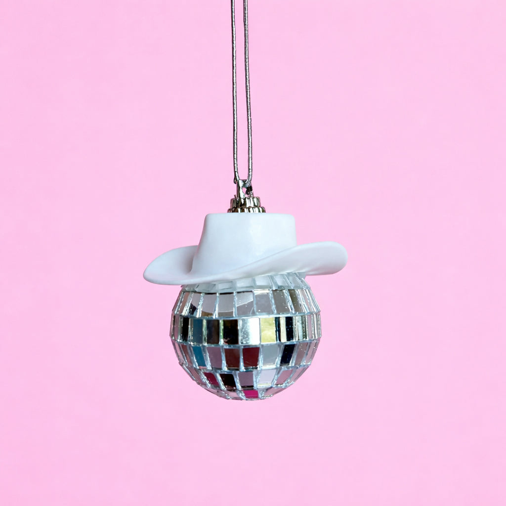 White disco cowgirl car mirror charm with a mini cowboy hat and mirrored disco ball on a soft pink background.