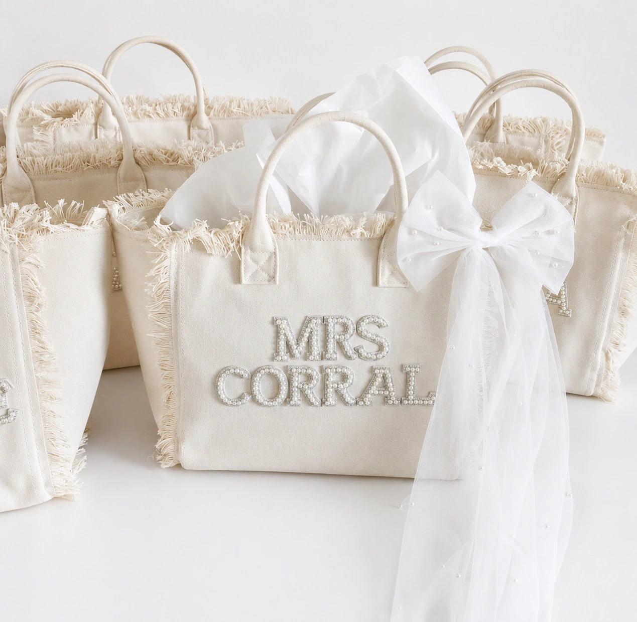 White personalised  tote bag with 'MRS CORRAL' text and decorative bow on a white background