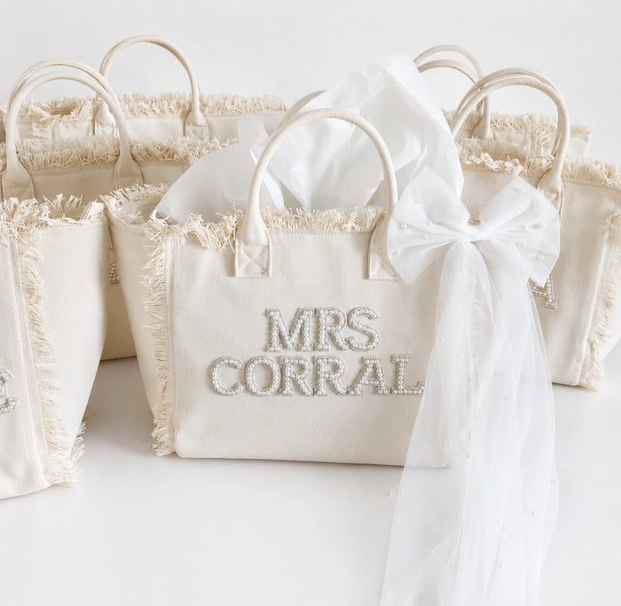 White personalised  tote bag with 'MRS CORRAL' text and decorative bow on a white background