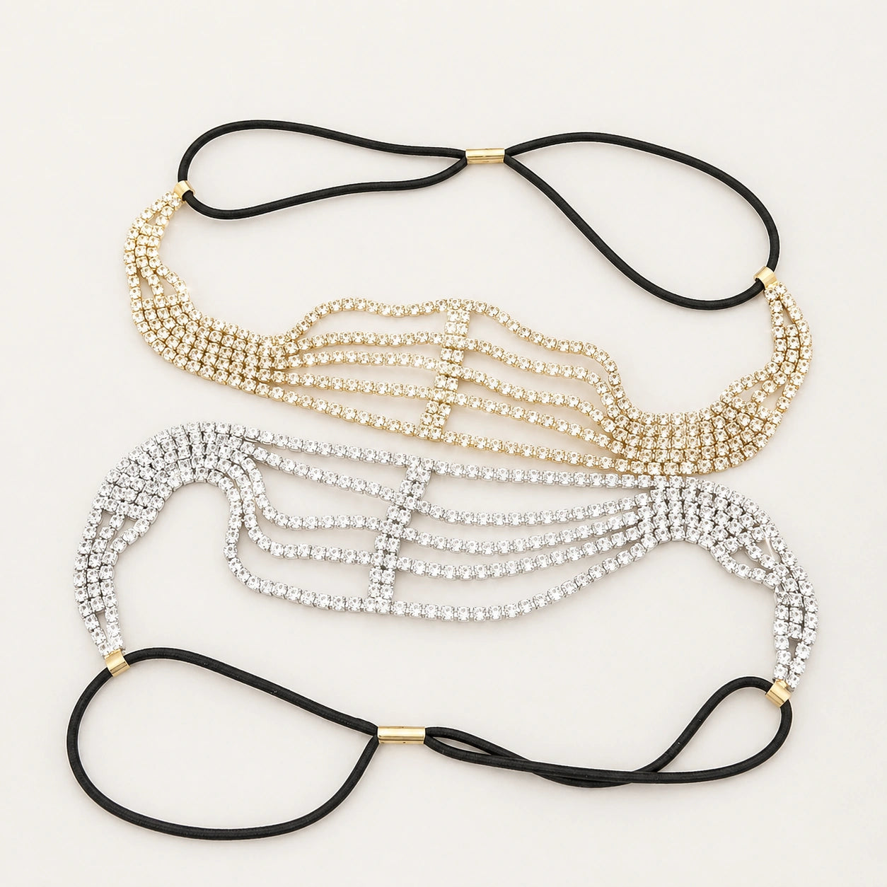 Two rhinestone headbands in gold, silver, and black on a white background