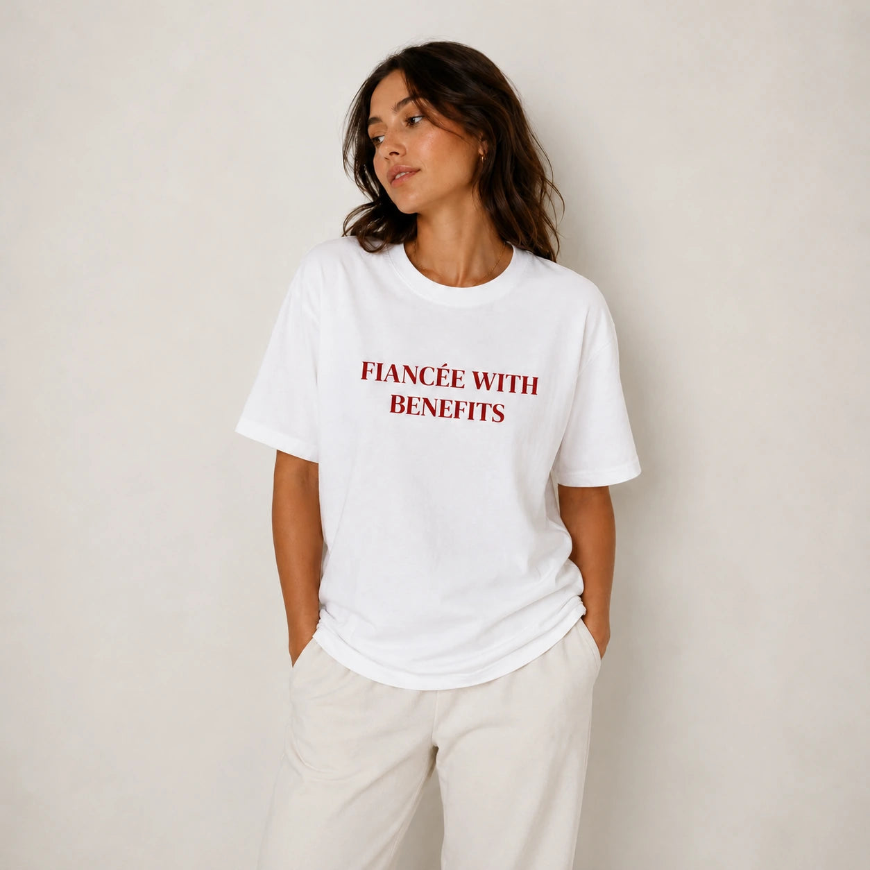 Woman wearing a white t-shirt with red text against a plain background