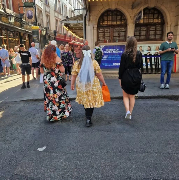 Bride wearing a white bow veil while walking with friends during a hen party weekend