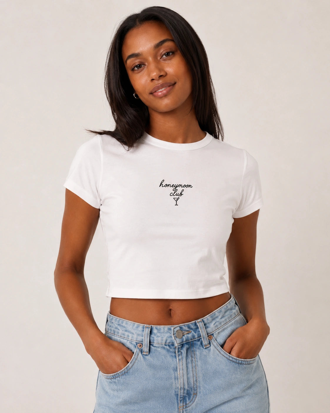 Woman wearing a white t-shirt with text and blue jeans on a plain background