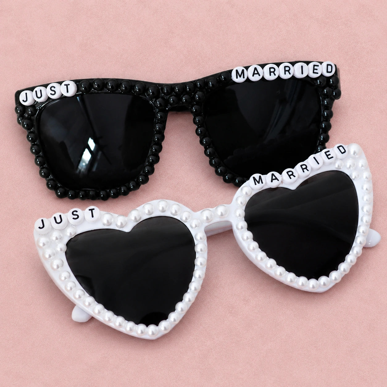 Heart-shaped sunglasses with 'Just Married' text on a pink background
