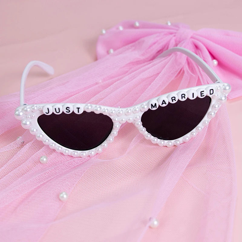 Sunglasses with 'Just Married' text on a pink fabric background