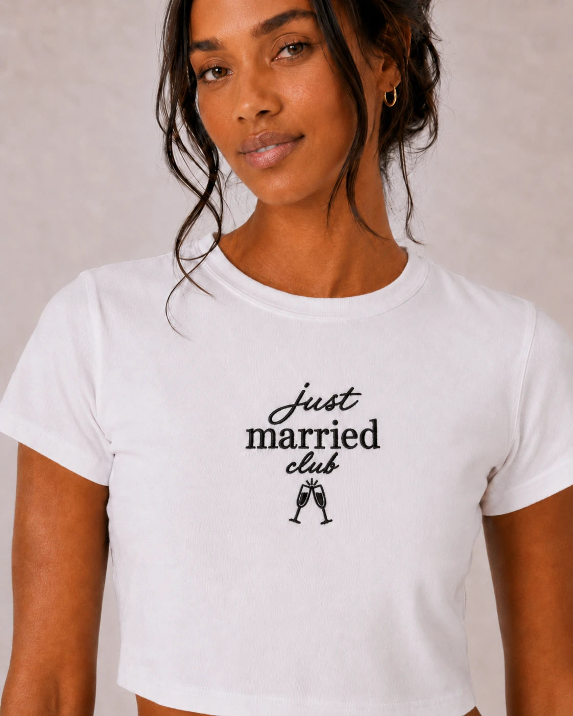 Woman wearing a white t-shirt with 'Just Married Club' text and champagne glass icons.