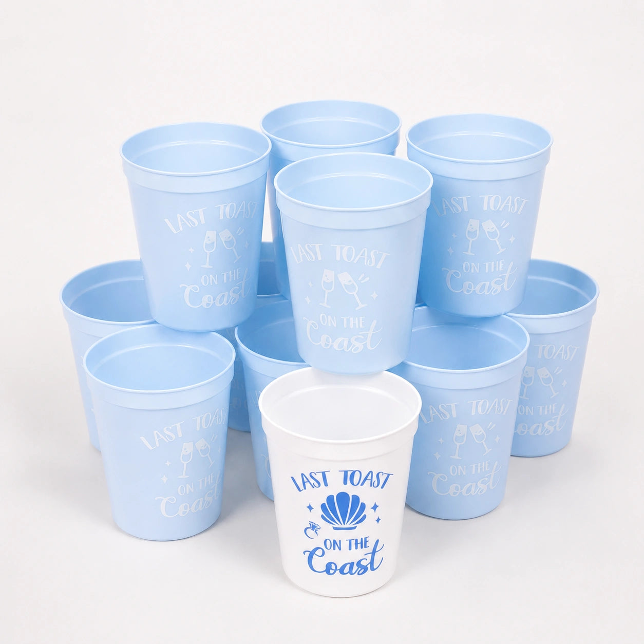 Set of blue plastic cups with 'Last Toast on the Coast' text and a white cup with similar text.