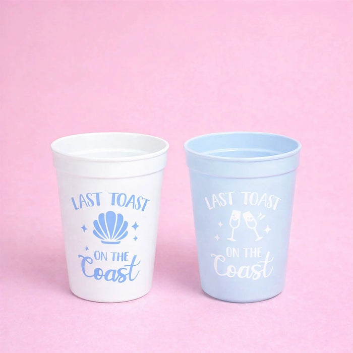 Two cups with 'Last Toast on the Coast' text and shell design on a pink background