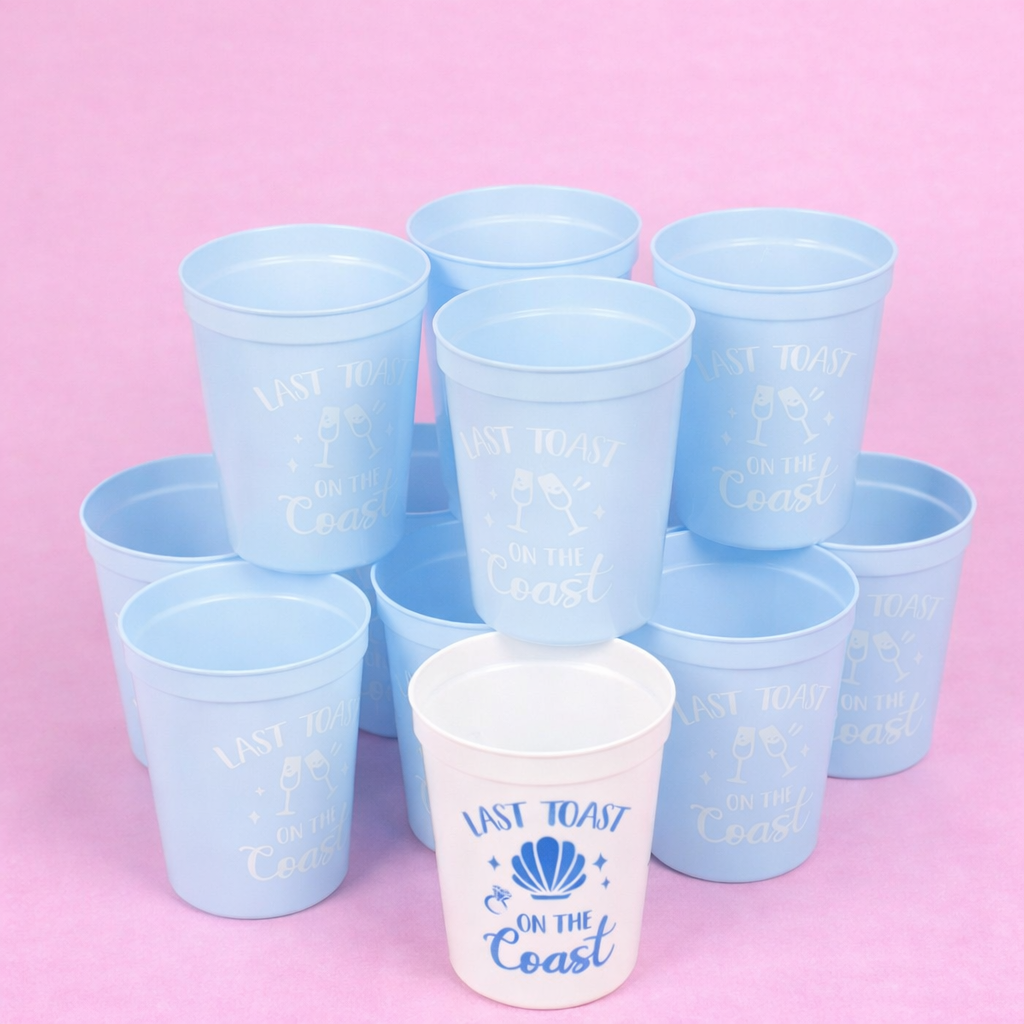Set of blue plastic cups with 'Last Toast on the Coast' text on a pink background