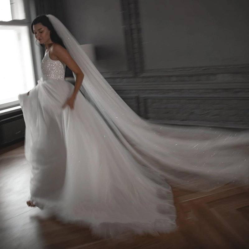 Woman in a white wedding dress with a long train in a room with large windows.