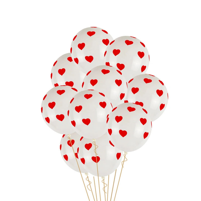 A cluster of white latex balloons printed with small red hearts, tied together with thin gold-colored strings against a plain white background.