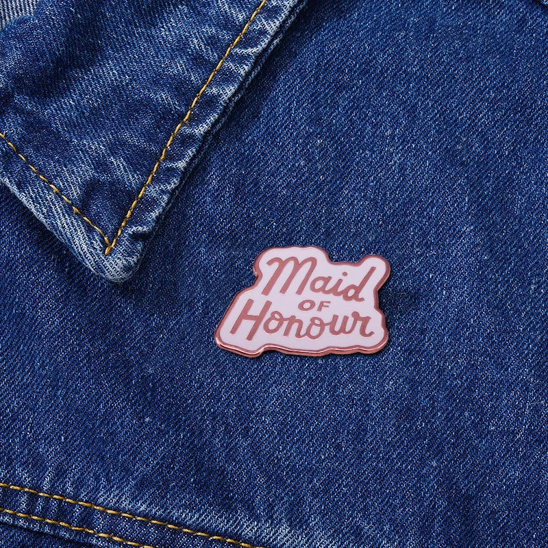 Denim jacket with a 'Maid of Honour' pin on a blue denim background
