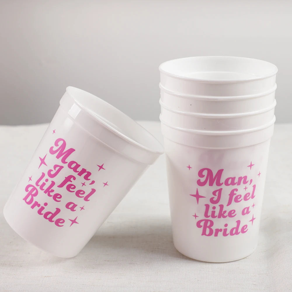 White plastic cups with pink text 'Man, I feel like a Bride' on a white surface.
