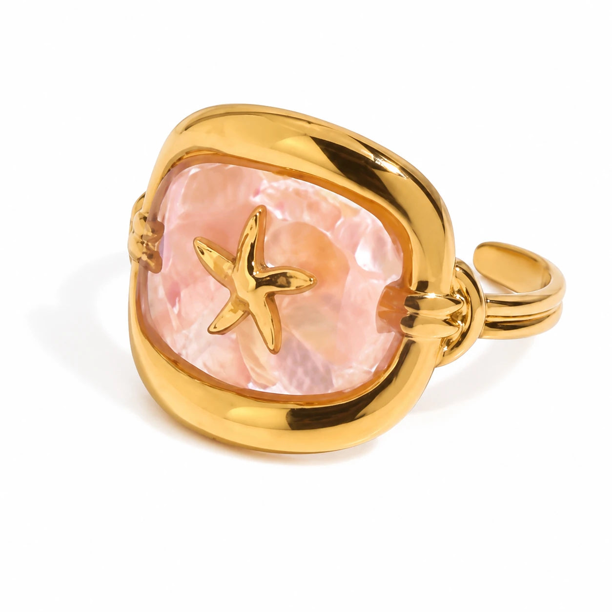 A gold ring featuring a large, irregularly shaped pink cabochon stone with a gold starfish motif set into the center, shown on a clean white background.