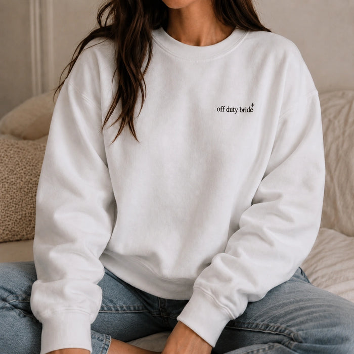 Person wearing a white sweatshirt with 'off duty bride' text sitting on a couch.