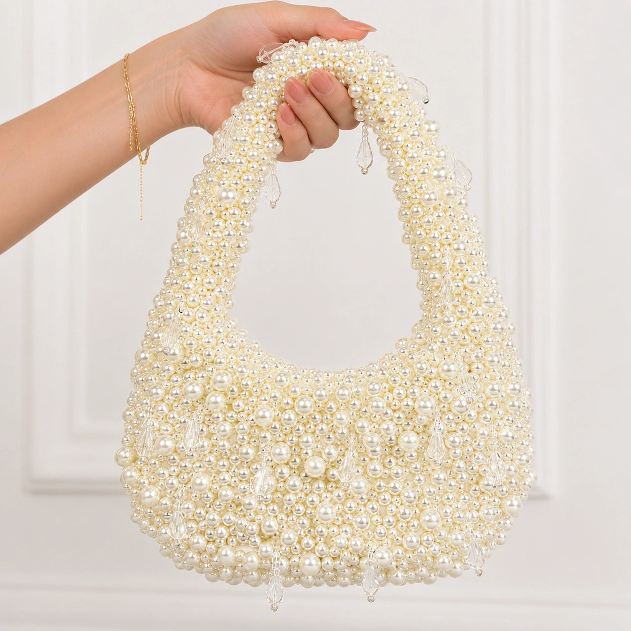 Pearl-handled handbag held by a hand against a white background