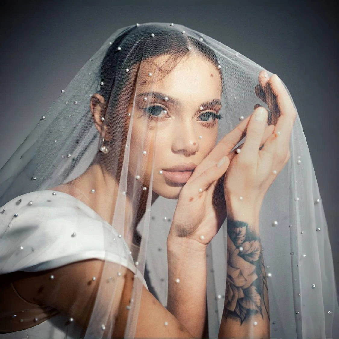 Beauty close-up of bride wearing a pearl-dotted bridal veil with soft tulle and romantic wedding styling.