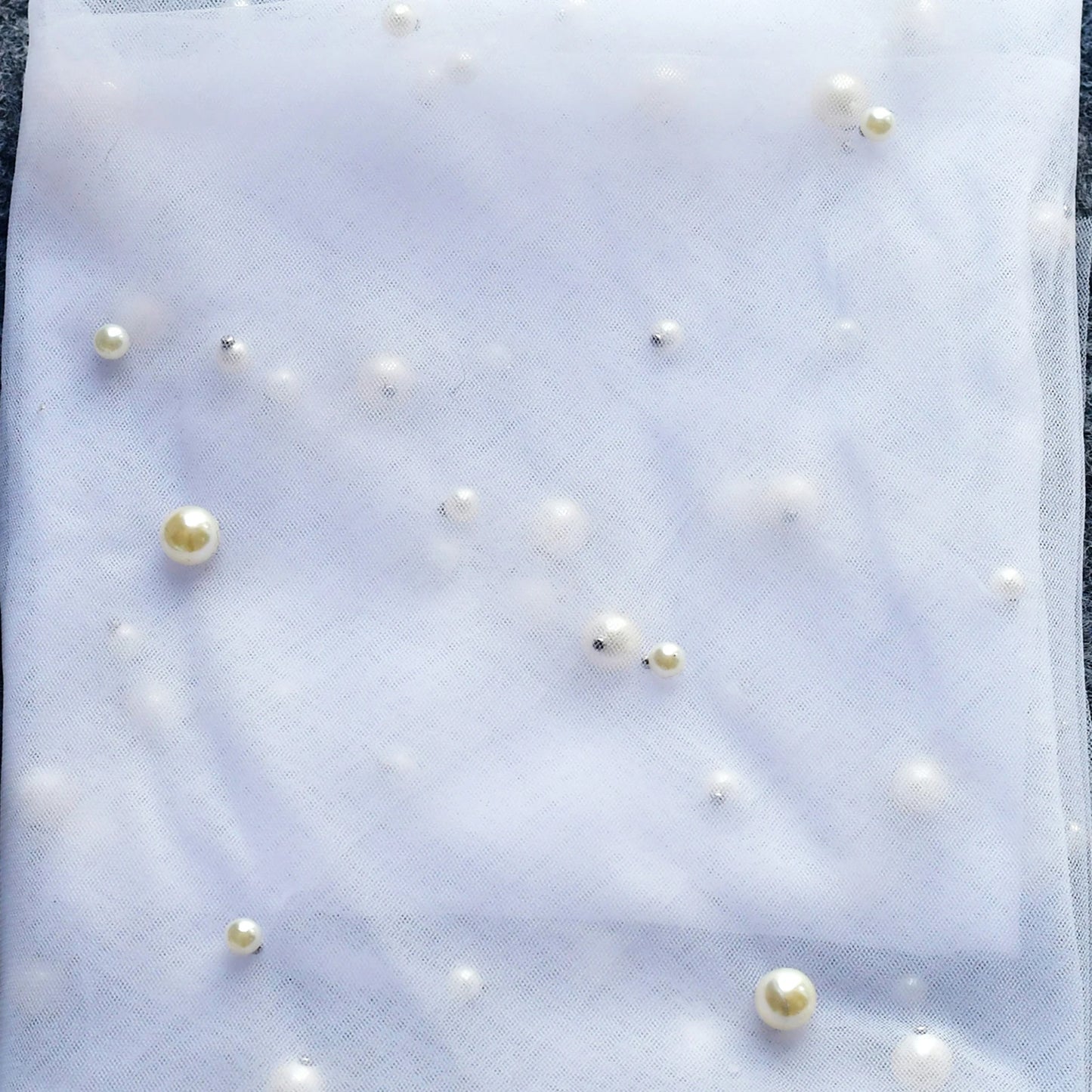 Pearl detail close-up on soft bridal veil tulle with delicate scattered pearl-style accents.