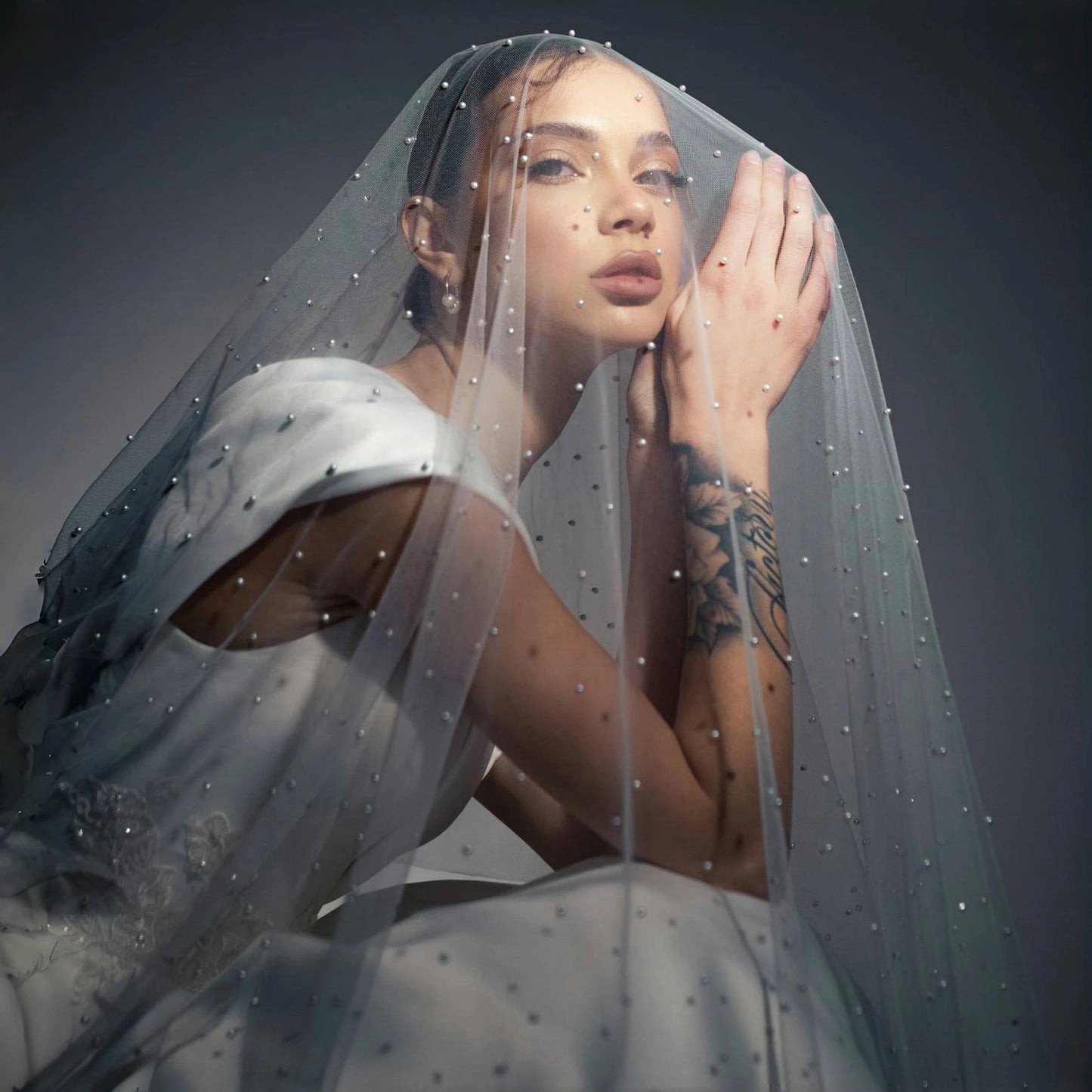 Romantic bride portrait wearing a soft pearl-dotted veil with delicate tulle and bridal styling.