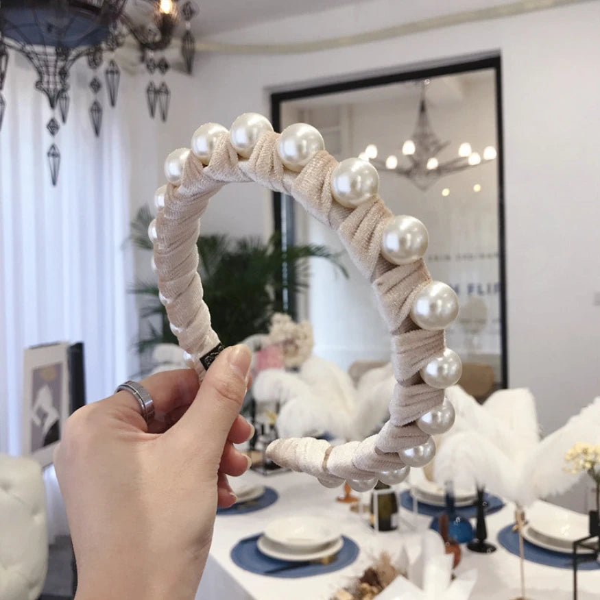Round mirror with pearl-like beads held by a hand in an indoor setting.